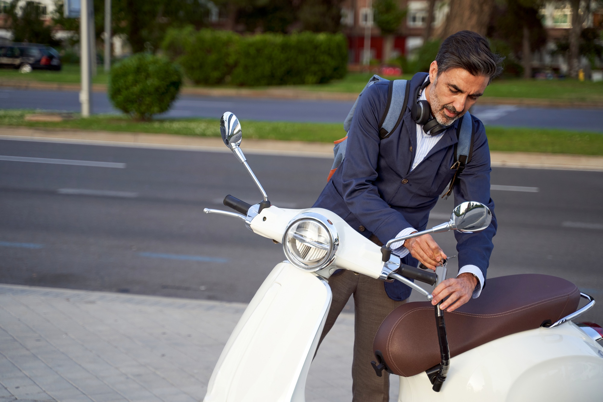 Adult male unlocking security lock on his white scooter. Anti-theft protection concept.