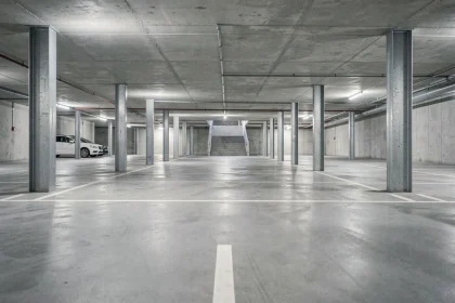 Parking souterrain moderne avec places délimitées en blanc sur béton gris, perspective grand angle montrant l'architecture structurelle d'un investissement immobilier