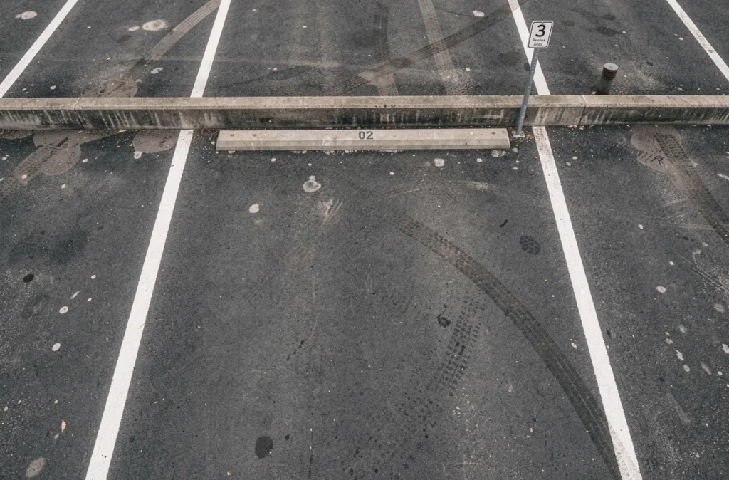 Vue aérienne d'une place de parking numérotée avec marquage au sol blanc sur asphalte sombre, symbole d'un investissement immobilier locatif